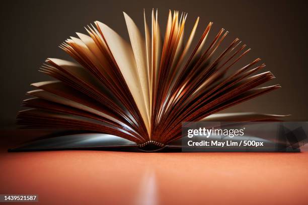 close-up of book on table against black background - book pages stock pictures, royalty-free photos & images