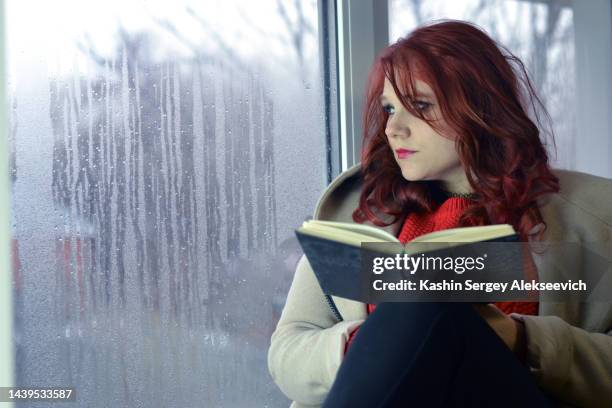 a young woman sitting at window. - woman lipstick rearview stock pictures, royalty-free photos & images