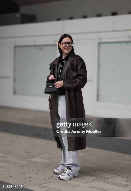 Maria Barteczko seen wearing a brown vegan leather trenchcoat by low classic, a black white knit polo shirt by Valentine Witmeur Lab, grey wide leg...