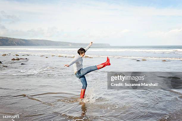 woman standing in sea - bota vermelha - fotografias e filmes do acervo