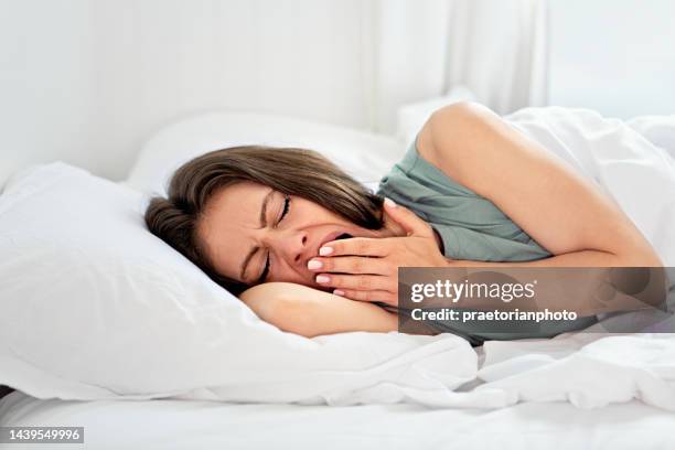 ベッドであくびをする若い女性 - あくび ストックフォトと画像