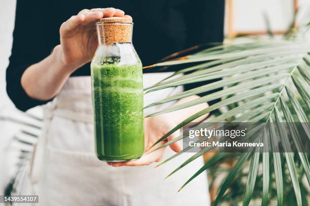 green smoothie at the bottle. - saftpresse stock-fotos und bilder