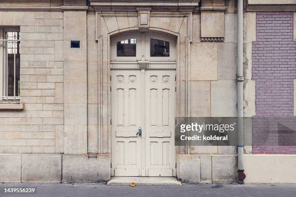 white wooden classic double doors of elegant european building in paris, france - french doors stockfoto's en -beelden