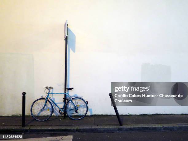 a bicycle attached to an urban sign post on a street at night in paris - street light post stock pictures, royalty-free photos & images