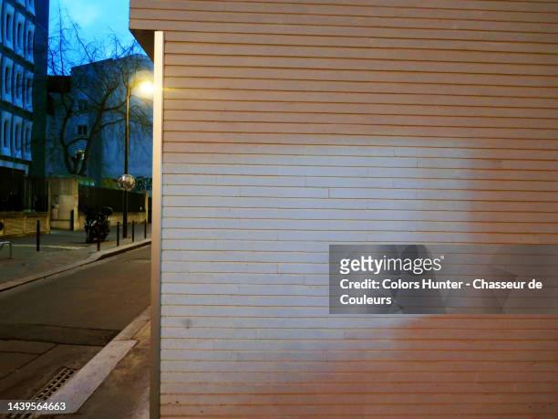 white wall between shadow and light with street at night in paris - wall night stock-fotos und bilder