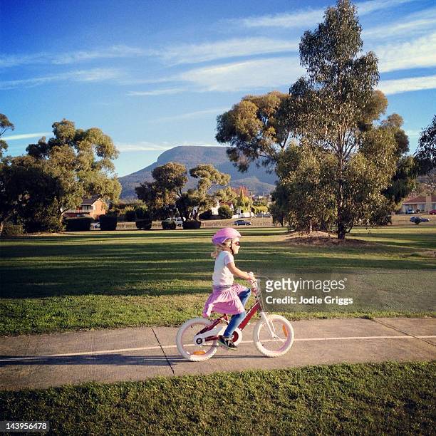 girl riding bike along path - girl bike stock pictures, royalty-free photos & images