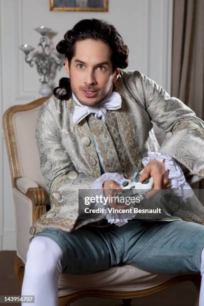 a man in 18th century garb using a games console - france costume stockfoto's en -beelden