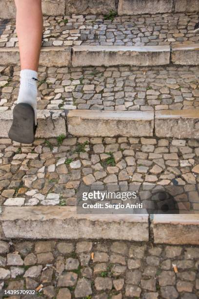 foot wearing slides and sports sock on a patterned stone steps - cobblestone pattern stock pictures, royalty-free photos & images