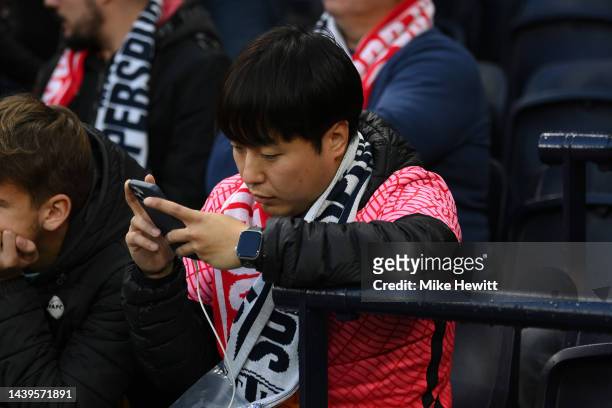 Fan checks their phone ahead of the Premier League match between Tottenham Hotspur and Liverpool FC at Tottenham Hotspur Stadium on November 06, 2022...