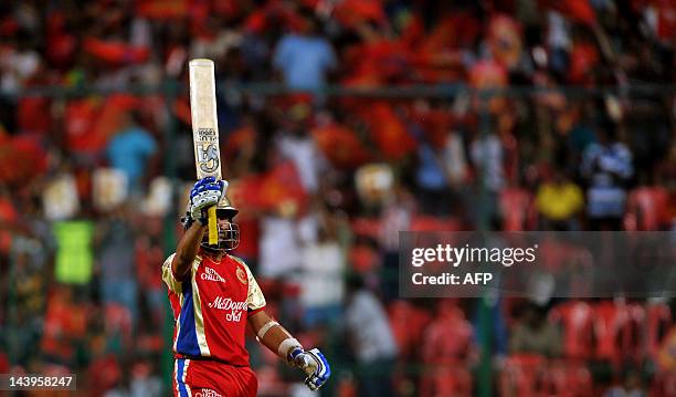 Royal Challengers Bangalore batsman Tilakaratne Dilshan raises his bat to celebrate his 50 runs during the IPL Twenty20 cricket match between Royal...