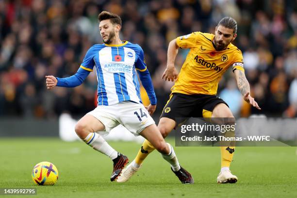 Adam Lallana of Brighton & Hove Albion is challenged by Ruben Neves of Wolverhampton Wanderers during the Premier League match between Wolverhampton...