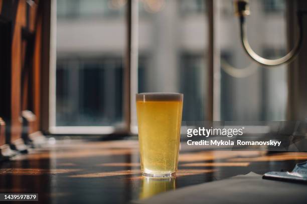the glass of beer on a wooden table in a cafe. - empty beer glass stock pictures, royalty-free photos & images