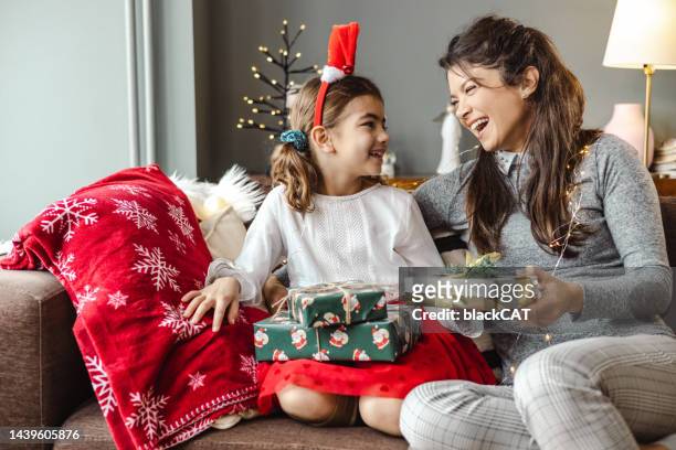 a mother gives her daughter a christmas present - santa giving out presents stock pictures, royalty-free photos & images
