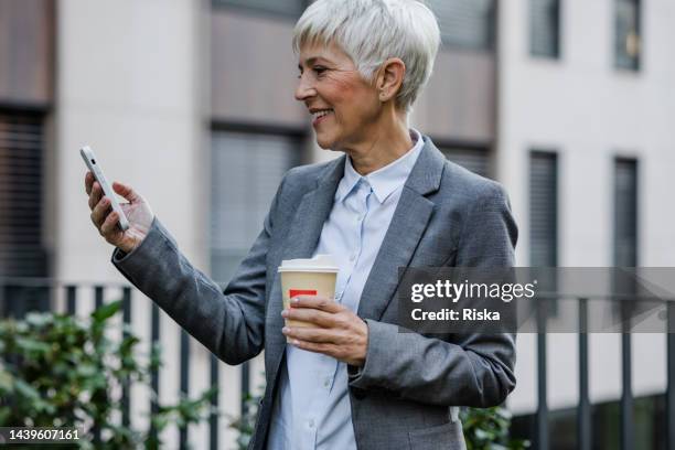 portrait of a senior businesswoman holding smartphone - managing director stock pictures, royalty-free photos & images