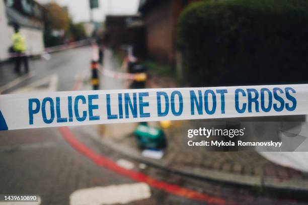 police white and blue cordon tape separating the crime scene. - groot brittannië stockfoto's en -beelden
