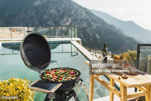 poolside barbecue party outdoors at sunset. vegetables on grill - picknick edel stock-fotos und bilder