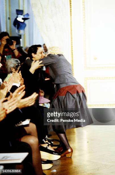 Designer Vivienne Westwood embraces designer Azzedine Alaïa while walking the runway at show finale.