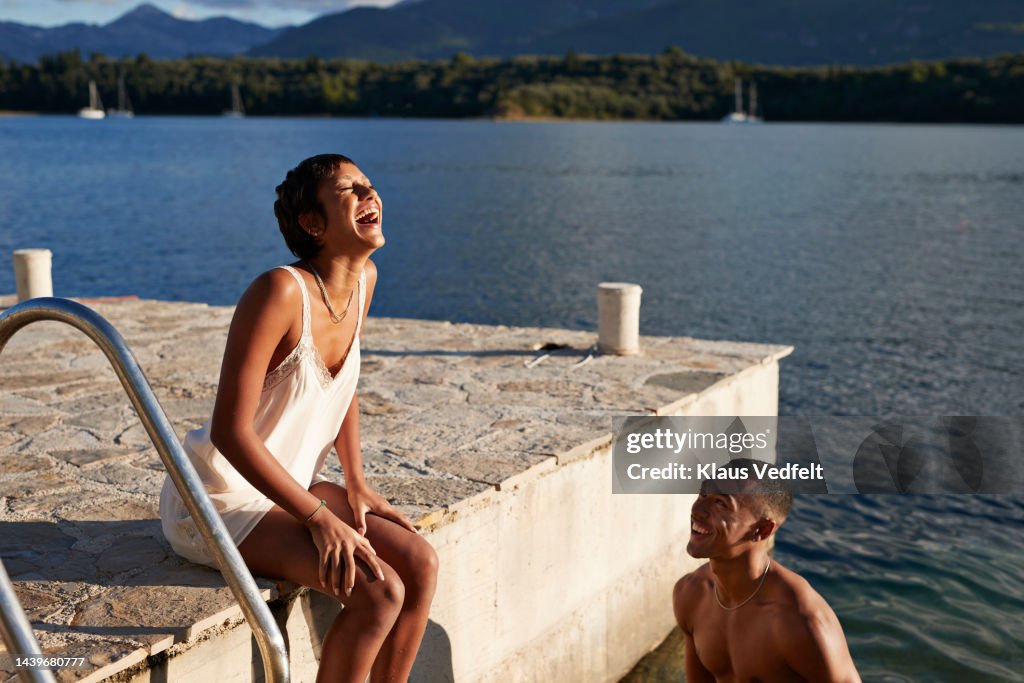 Smiling man looking at friend laughing on pier