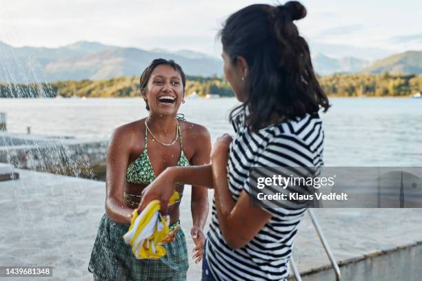 young woman laughing while enjoying with friend - women in wet tee shirts stock pictures, royalty-free photos & images