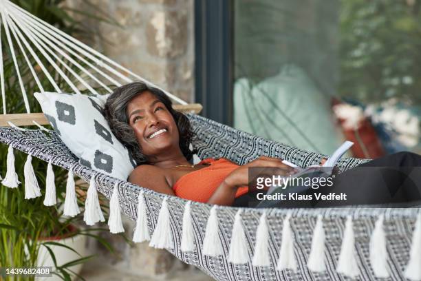 woman with book relaxing in hammock - escapism reading stock pictures, royalty-free photos & images