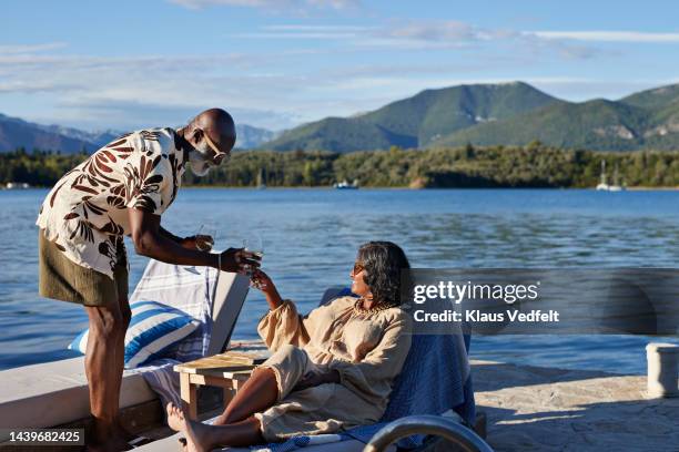 man giving wineglass to woman on deck chair - navy wife stock pictures, royalty-free photos & images