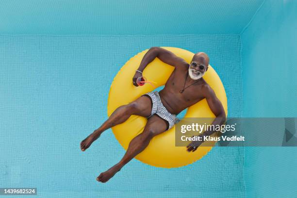 man relaxing in yellow inflatable ring - calções azuis imagens e fotografias de stock