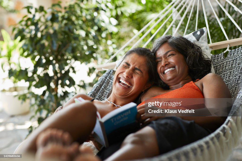 Cheerful woman lying with mother in hammock