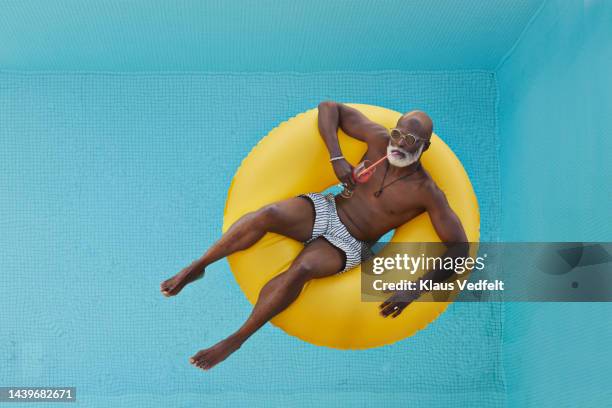 bald man relaxing in yellow inflatable ring - man in swimming pool stockfoto's en -beelden