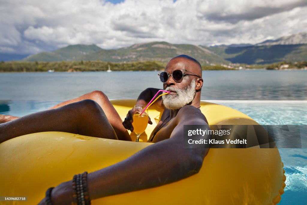 Man drinking juice in inflatable ring