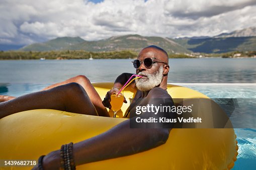 Man drinking juice in inflatable ring Man drinking juice in inflatable ring