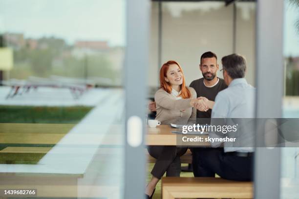 glückliches paar kam zu einer vereinbarung mit versicherungsvertreter im büro. - kundenbeziehung stock-fotos und bilder