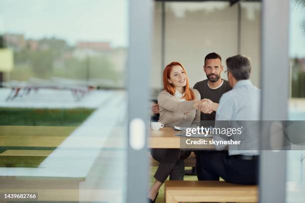 happy couple came to an agreement with insurance agent in the office. - warranty stockfoto's en -beelden