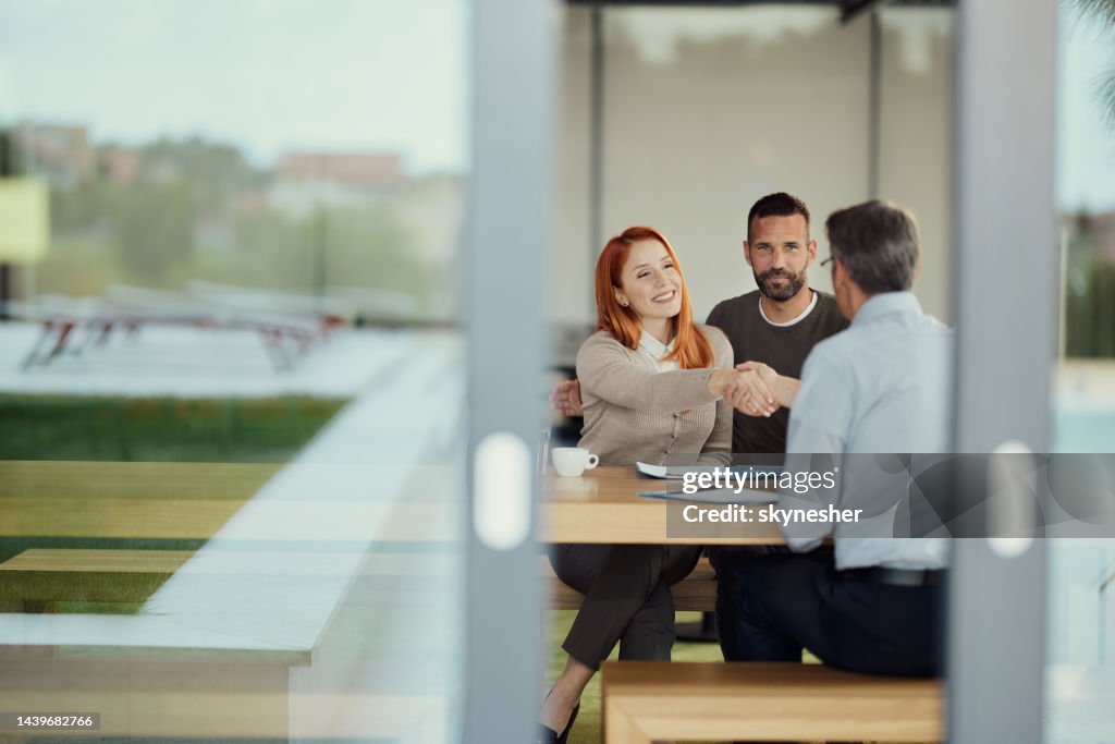Happy couple came to an agreement with insurance agent in the office.
