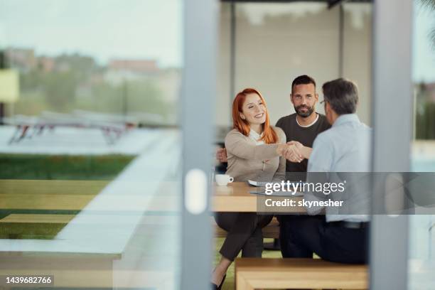 casal feliz chegou a um acordo com o agente de seguros no escritório. - corretor de imóveis - fotografias e filmes do acervo