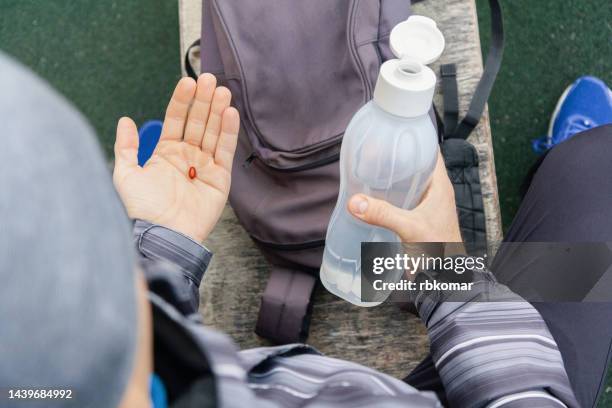 athlete taking coenzyme nutritional supplement while outdoor workout - coq10 stock pictures, royalty-free photos & images