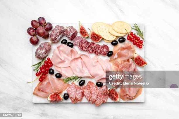 сharcuterie board with salami and prosciutto served with olives and grapes. snacks in the restaurant for an aperitif or a family dinner - charcuterie stockfoto's en -beelden