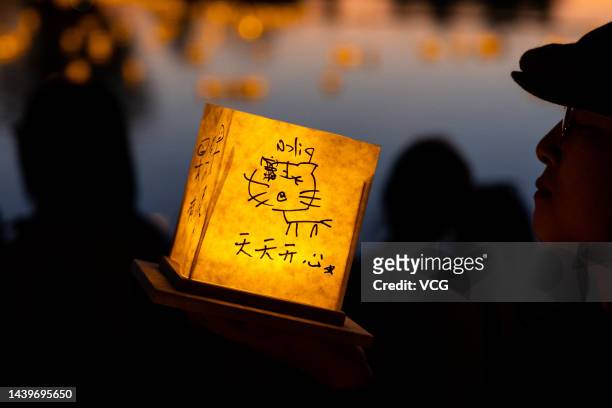 Man holds a decorated water lantern before releasing it into water during the Water Lantern Festival on November 5, 2022 in Los Angeles, California.