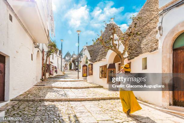 tourist walking in the picturesque village of alberobello, puglia, italy - trulli fotografías e imágenes de stock