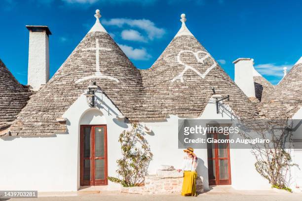 woman sitting under a trullo in the picturesque village of alberobello, puglia, italy - puglia italy stock pictures, royalty-free photos & images