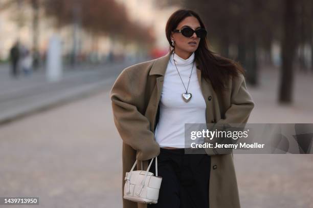 Anna Winter is seen wearing black Céline sunglasses, silver The Good statement heart chain/long necklace, white turtleneck from Weekday, beige long...