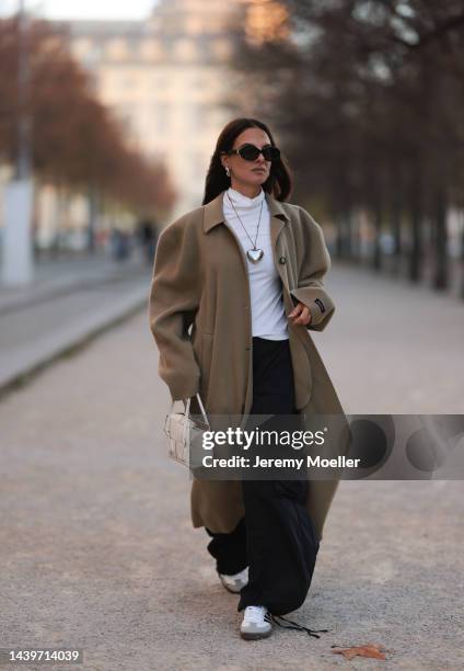 Anna Winter is seen wearing black Céline sunglasses, silver The Good statement heart chain/long necklace, white turtleneck from Weekday, beige long...