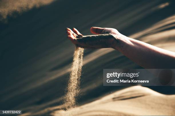 woman letting sand slip through her fingers. - hand touch stock pictures, royalty-free photos & images