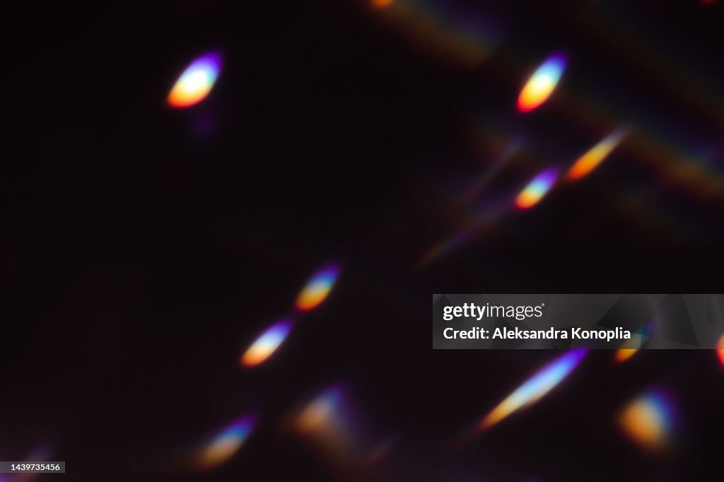 Colourful rainbow disco ball light leaks texture on black background