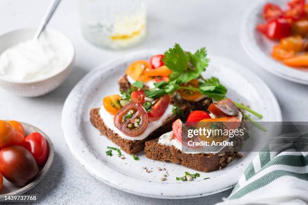 healthy rye bread toast with soft white cheese and tomatoes - roggebrood stockfoto's en -beelden