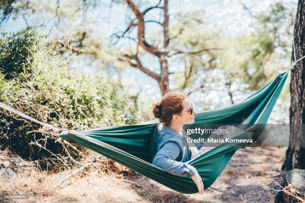 Woman relaxing in hammock in the forest near the sea.