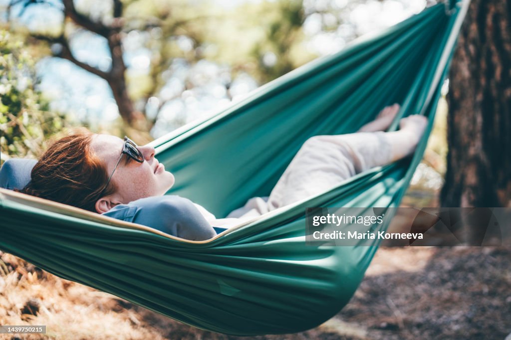 Woman relaxing in hammock in the forest near the sea.
