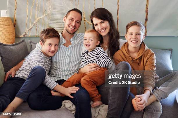 a family with three young boys is sitting on the sofa in their living room - saxony stockfoto's en -beelden