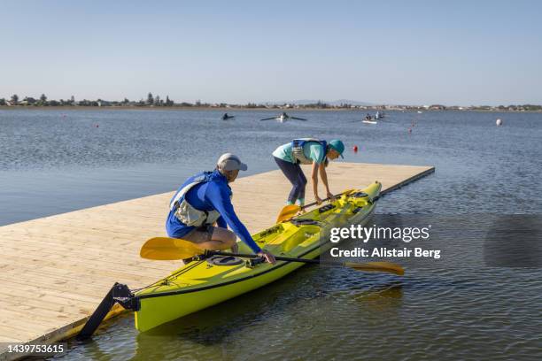 couple preparing a kayak for a trip out on a lake in summer - seniors canoeing stock pictures, royalty-free photos & images