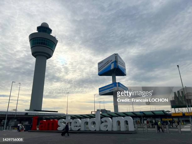 Passager passant devant la tour de contrôle et le slogan "I amsterdam" à l'aéroport d'Amsterdam-Schiphol le 29 octobre 2022.