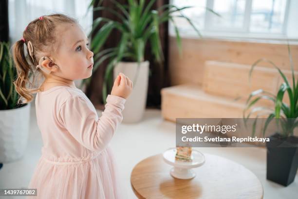 child with cochlear implant eating rainbow cake for his birthday at home - cochlea stock pictures, royalty-free photos & images